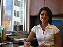 Picture of Elizabeth Alsop sitting at a desk, with downtown Denver in the background