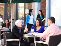 Image of people having a discussion at an a table outside